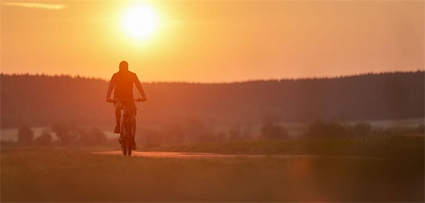 Ein Radfahrer ist am Morgen im Sonnenaufgang unterwegs.