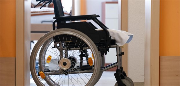 Ein Rollstuhl steht in einem Altenheim vor einem Zimmer