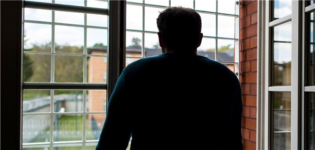 Ein Straftäter steht vor einem vergitterten Fenster in der Klinik für Forensische Psychiatrie auf dem Gelände des Martin Gropius Krankenhauses in Eberswalde (Brandenburg).