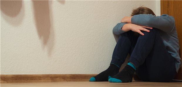 Nationaler Pakt gegen sexualisierte Gewalt an Kindern gefordert Ein Kind kauert in der Decke, dunkle Schatten liegen an der Wand.