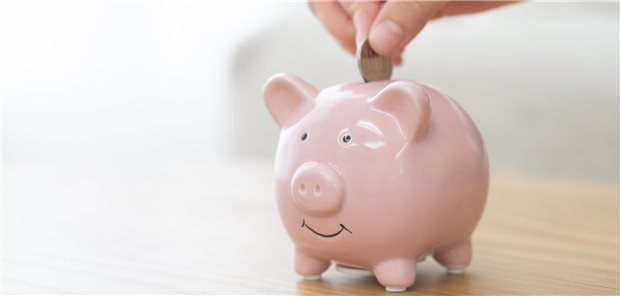 Jemand wirft einen Münze in ein rosa Sparschwein