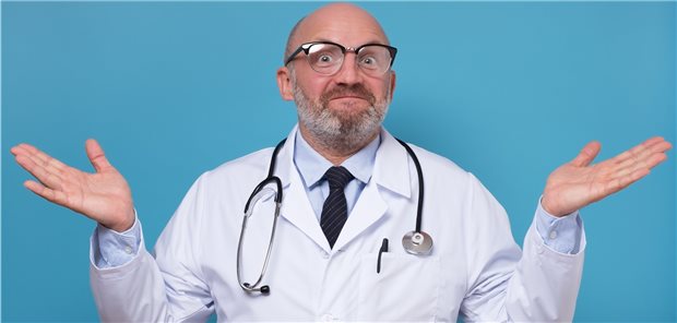 Mann mit grauem Bad im Kittel mit Stethoskop um den Hals zuckt die Schultern und blickt ratlos - Symbolbild mit Fotomodell.