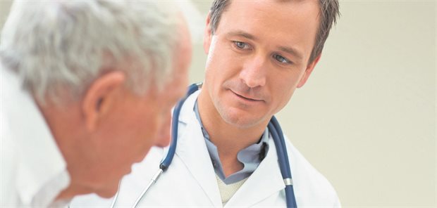 Ein arzt schaut einem alten Patienten genau ins Gesicht