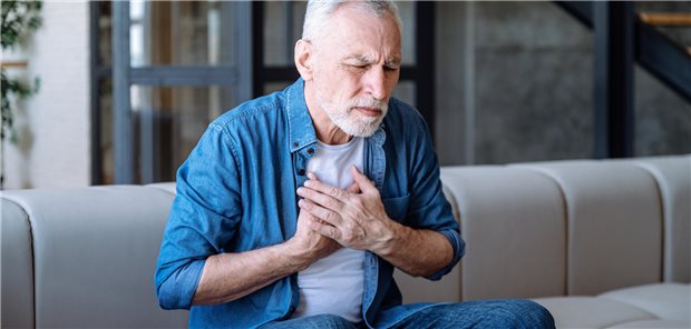 Mann fast sich mit schmerzverzerrtem Blick an die Brust