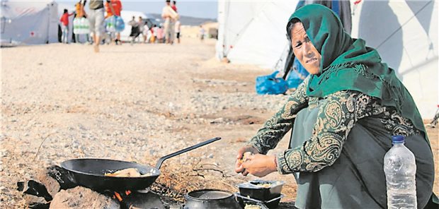 Hilfseinsatz in Lesbos, der nachhallt Eine Frau im Flüchtlingslager auf Lesbos bereitet Essen zu.