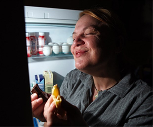 Bei Binge-Eating hilft Psychotherapie Eine Frau nachts am Kühlschrank: Die Binge-Eating-Störung ist durch wiederkehrende Essanfälle gekennzeichnet.