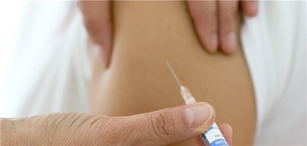 Man sieht eine Spritze und eine Schulter.