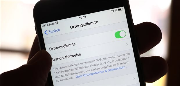 Das Handy als Geheimwaffe im Kampf gegen das Coronavirus? Eine Hand hält ein iPhone, in dessen Menü die Ortungsdienste aktiviert sind. Zur Bekämpfung der Ausbreitung des Coronavirus wird die Nutzung von Handydaten diskutiert.
