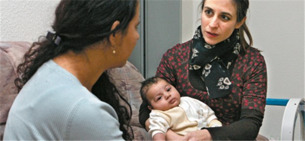 Hebammen mit speziellem Blick für Probleme Eine Hebamme (r.) unterhält sich mit der Mutter eines Babys.