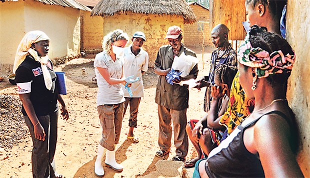 Helfer sehen Hoffnungsschimmer Eine Mitarbeiterin von "Ärzte ohne Grenzen" erklärt einer Familie in Südguinea, wie die Schutzhandschuhe zu benutzen sind.