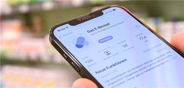E-Rezept-App auf einem Smartphone, im Hintergrund unscharf Medikamente.
