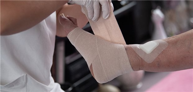 Eine Pflegefachkraft legt in der ambulanten Pflege einen Kompressionsverband an. Gesundheitlich geht es vielen Beschäftigten in der Pflege nicht gut, Krankenstand und Fehlzeiten sind hoch.