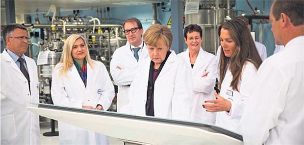 Merkel auf Visite bei Roche Eine Roche-Mitarbeiterin zeigt Bundeskanzlerin Angela Merkel, wie die Maschinen und Arbeitsprozesse des Pharmakonzerns funktionieren.