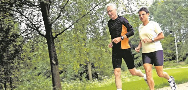 Ein Seniorenpaar beim joggen im Wald.