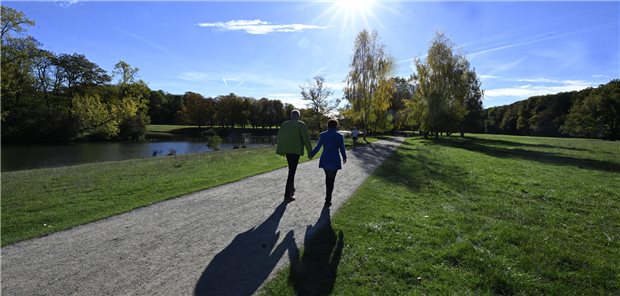 Ein älteres Paar geht an einem Fluss spazieren.