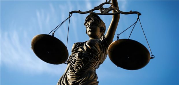 Eine Statue der Justitia hält eine Waage in der Hand.