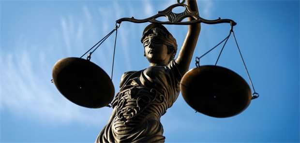 Eine Statue der Justitia hält eine Waage in der Hand.