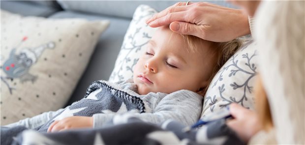 Krankes Kleinkind, das mit Fieber im Bett liegt und sich zu Hause ausruht.