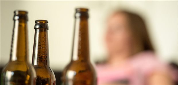 Umfrage zur Alkoholwerbung: Mehrheit der Bundesbürger für Warnhinweise Eine junge Frau sitzt hinter leeren Bierflaschen.