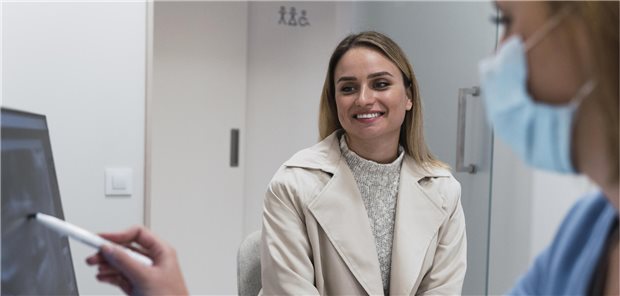 Patienten lacht. während MFA ihr etwas am PC zeigt.