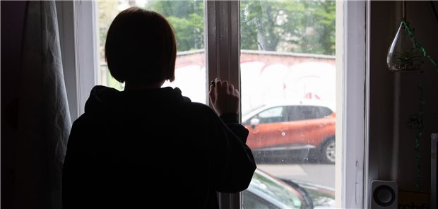 Person steht am Fenster.