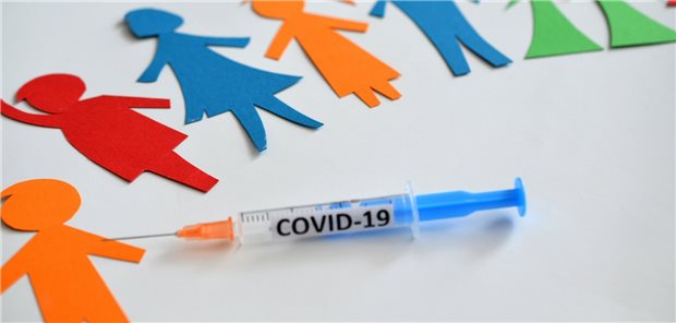 Ethikratmitglied fordert Corona-Impfpflicht für Lehrkräfte und Kita-Personal Ausgeschnittene Menschen in verschiedenfarbigen Papier auf einem Tisch, davor eine COVID-19-Impfnadel.