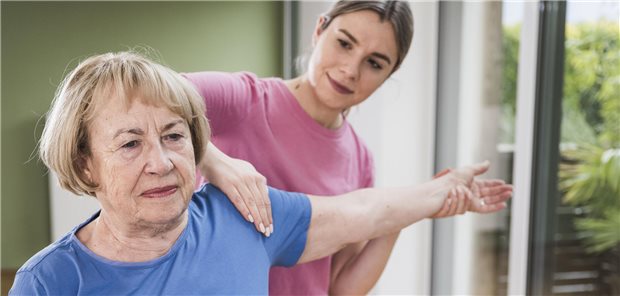Eine Physiotherapeutin behandelt die Schulter einer Patientin.