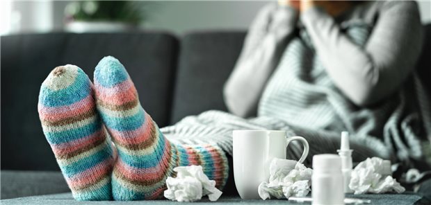 Eine Frau sitzt mit dicken Wollsocken auf der Couch.