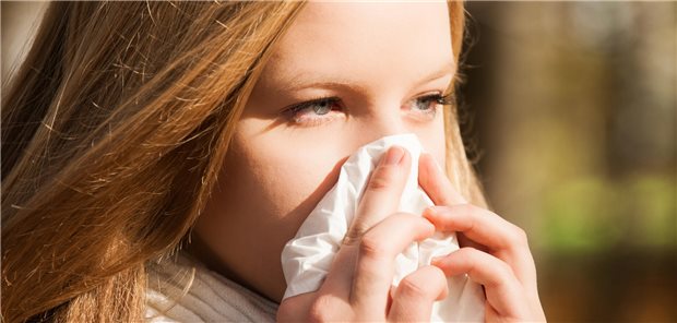 Eine junge Frau putzt sich die Nase