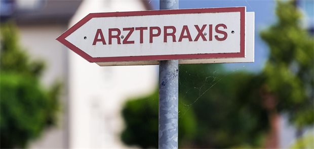 Ein rot-weißes Schild an einer Straße mit der Aufschrift "Arztpraxis".