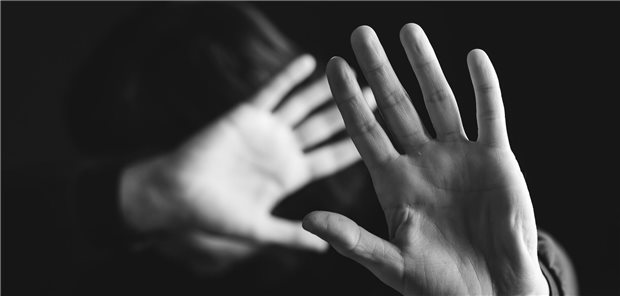 Nahaufnahme einer Frau, die schützend ihre Hände abwehrend vor ihrem Körper und Gesicht hält. 