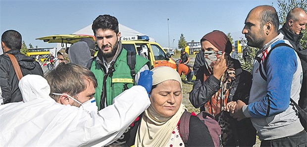WHO gibt Gesundheitssektor Risiko-Checkliste an die Hand Erstversorgung bei der Ankunft in Deutschland: Ein DRK-Helfer untersucht eine Syrerin.