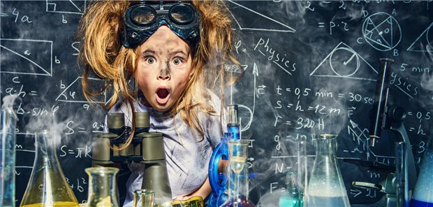 Mädchen geht chemischen Experimenten in einem Klassenzimmer nach, die Haare stehen ihr zu Berge.