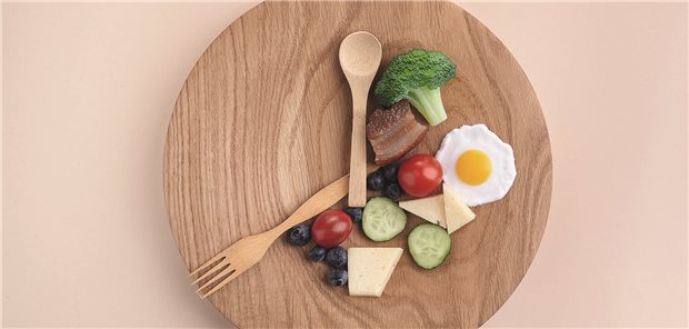 Was bringt Fasten bei Schmerz? Ein Teller mit Essen, das Bestreck ist wie Uhrzeiger positioniert.