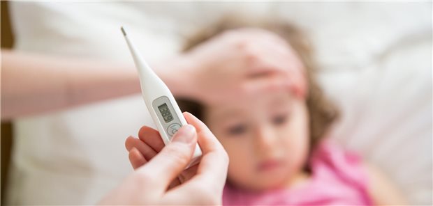 Fiebermanagement in der Praxis: Worauf es bei Kindern wirklich ankommt Ein Kind liegt im Bett, im Vordergrund ist ein Fieberthermometer zu sehen.