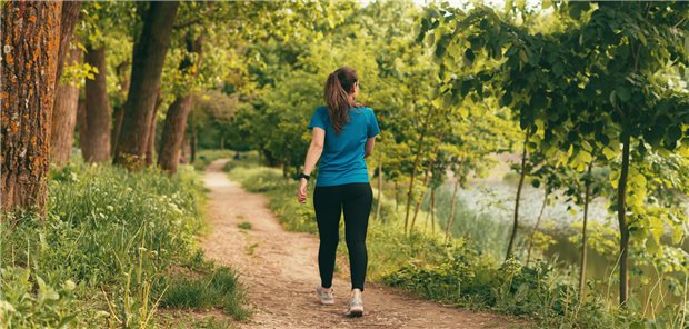 Eine junge Frau spaziert durch den Wald.