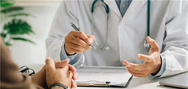 Ein Arzt in einem weißen Arztkittel spricht mit einem männlichen Patienten über die Ergebnisse der medizinischen Untersuchung und gibt anhand dieser eine Behandlungsempfehlung ab.