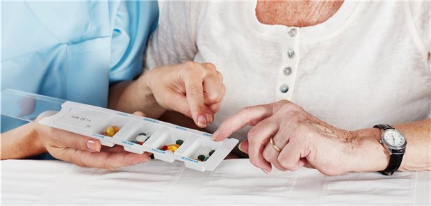 Ältere Dame und Helferin zeigen auf und betrachten Tabletten.