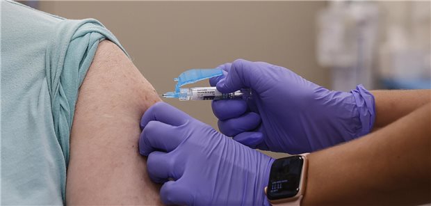 Impfung per Spritze in einen entblößten Oberarm.