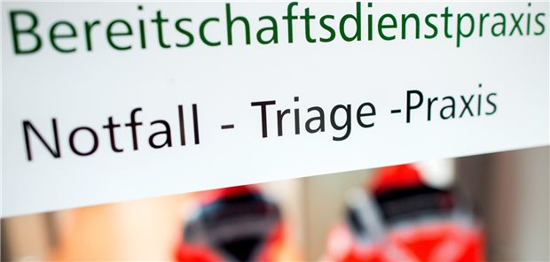 Sanitäter unter einem Schild mit der Aufschrift "Bereitschaftsdienstpraxis Notfall - Triage - Praxis"