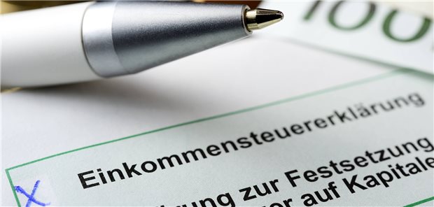 Geld, Kugelschreiber und ein angekreuztes Formular zur Einkommensteuererklärung.