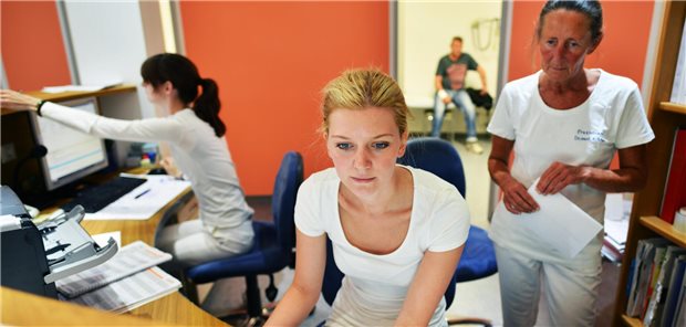 Drei Medizinische Fachangestellte bei der Arbeit am Empfang.