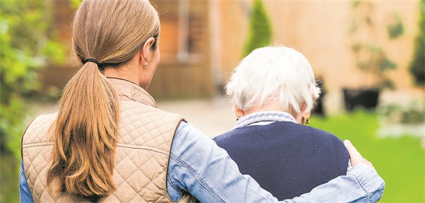 Eine junge Frau begleitet eine ältere Dame beim Spaziergang im Park.