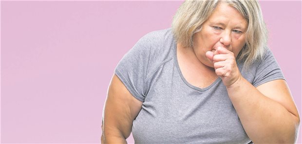 Eine übergewichtige Frau hustet und hält sich die Hand vor den Mund