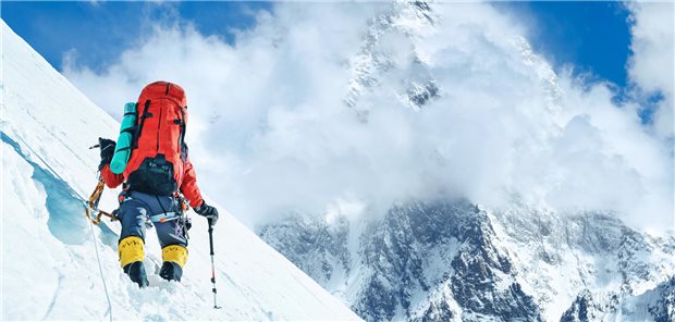 Bergsteiger läuft einen schneebedeckten Hang hinauf. 