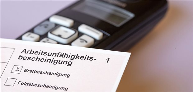 Eine AU-Bescheinigung vor einem Telefon.