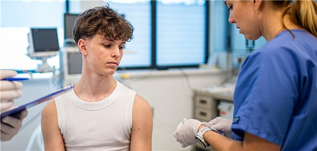 Ein junger Teenager erhält eine Memingokokken-Impfung in einer Arztpraxis. 