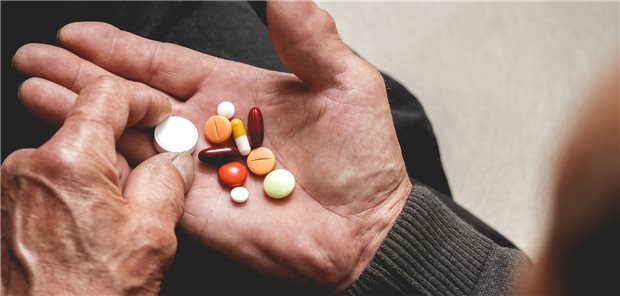 Ein Patient hält viele verschiedene Tabletten in seiner Hand.