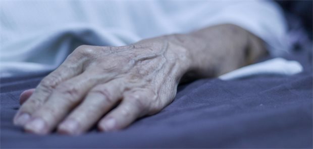 An Asian senior man’s hand relax on the bed side while sleeping