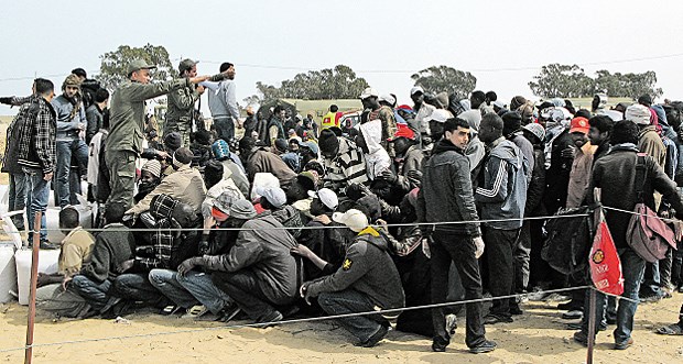 Tausende in Libyen auf der Flucht - es fehlt fast alles Geschafft: Flüchtlinge auf der tunesischen Seite der Grenze sitzen auf engstem Raum - überwacht von Polizisten.